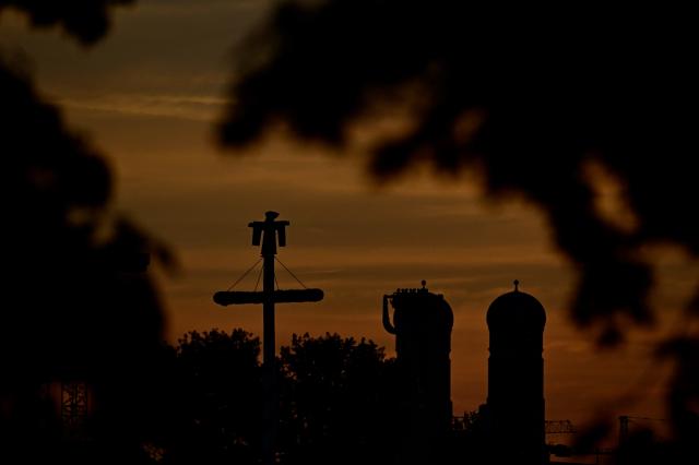 The steeples of the Frauenkirche (R, Church of Our Lady) and a so-called "Muenchner Kindl" figure silhouette against the morning sky at the Theresienwiese fair grounds prior to the opening of the 191st Oktoberfest beer festival in Munich, southern Germany on September 19, 2026. The world's biggest beer festival Oktoberfest runs until October 4, 2026 (Photo by Tobias SCHWARZ / AFP)
