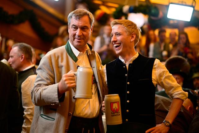 Bavaria's State Premier Markus Soeder (L) and the mayor of Munich Dominik Krause clink their beer mugs after the first barrel of beer was tapped with the traditional "O´zapft is!" (It's tapped!) to start Munich's annual beer festival, the Oktoberfest, on September 19, 2026 in Munich, southern Germany. The world's biggest beer festival Oktoberfest runs until October 4, 2026. (Photo by Tobias SCHWARZ / AFP)