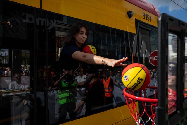 A member of the Slovak team from Bratislava throws a ball into the basket from a tram window as part of one of the challenges during the 12th European Tram Driver Championship in front of the Palace of Culture and Science on Marszalkowska Street in downtown Warsaw, on 19 September 2026. 26 teams – each consisting of a female and a male tram driver, from 25 cities and 24 European countries, plus one guest team from Melbourne, Australia – show off their driving skills in a series of challenging competitions that test their precision, concentration, feel for the vehicle, and control of the tram. (Photo by Wojtek RADWANSKI / AFP)