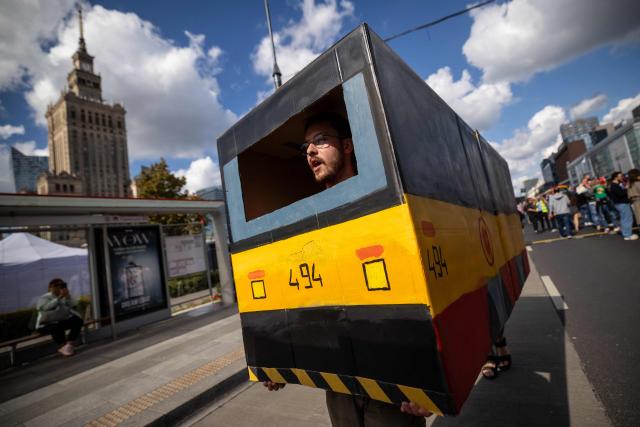 A group of fans dressed as a cardboard mock-up Warsaw tram is entertaining spectators during the 12th European Tram Driver Championship in front of the Palace of Culture and Science on Marszalkowska Street in central Warsaw on 19 September 2026. 26 teams – each consisting of a female and a male tram driver, from 25 cities and 24 European countries, plus one guest team from Melbourne, Australia – show off their driving skills in a series of challenging competitions that test their precision, concentration, feel for the vehicle, and control of the tram. (Photo by Wojtek RADWANSKI / AFP)