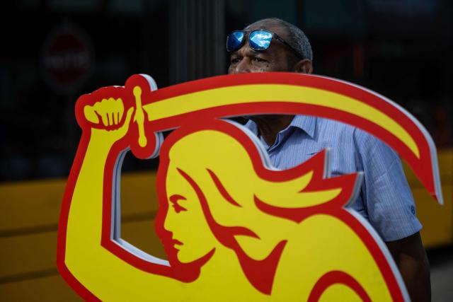 A member of Great Britain team from London is setting up a cardboard figure of the Warsaw Mermaid – the symbol of the town – during an competition focused on precisely avoiding obstacles during the 12th European Tram Driver Championship in front of Palace of Culture and Science on Marszalkowska street in Warsaw's downtown, on September 19, 2026. 26 teams – each consisting of a female and a male tram driver, from 25 cities and 24 European countries, plus one guest team from Melbourne, Australia – show off their driving skills in a series of challenging competitions that test their precision, concentration, feel for the vehicle, and control of the tram. (Photo by Wojtek RADWANSKI / AFP)