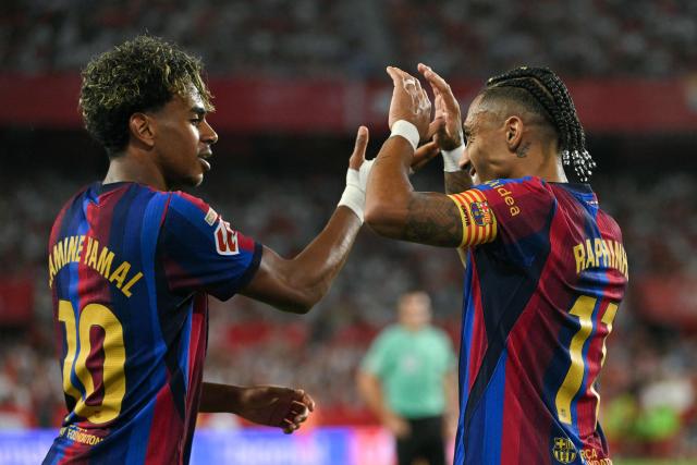 Barcelona's Brazilian forward #11 Raphinha (R) celebrates with teammate Spanish forward #10 Lamine Yamal after scoring his team's second goal during the Spanish league football match between Sevilla FC and FC Barcelona at the Ramon Sanchez Pizjuan stadium in Seville on September 19, 2026. (Photo by JORGE GUERRERO / AFP)