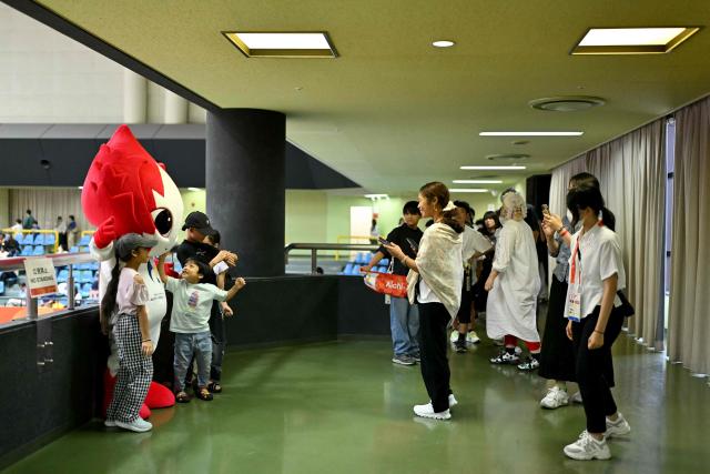 Spectators take photos with the 2026 Asian Games mascot Honohon, during a karate competition at the Toyohashi Gymnasium in Toyohashi, Aichi prefecture on September 20, 2026. (Photo by MOHD RASFAN / AFP)