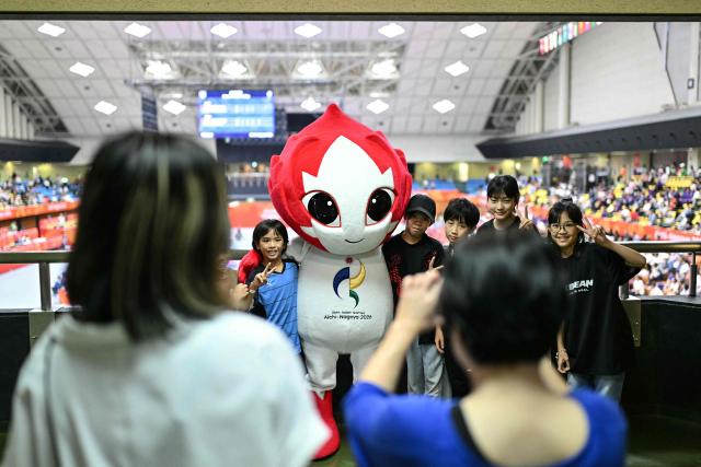 Spectators take photos with the 2026 Asian Games mascot Honohon, during a karate competition at the Toyohashi Gymnasium in Toyohashi, Aichi prefecture on September 20, 2026. (Photo by MOHD RASFAN / AFP)