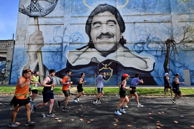 TOPSHOT - Runners compete in the Buenos Aires International Marathon as they pass in front of a mural depicting Argentine football legend Diego Maradona at La Boca neighborhood in Buenos Aires, on September 20, 2026. (Photo by Luis ROBAYO / AFP)