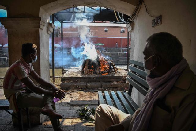 People watch the burning pyre of a flash flood victim during a funeral ceremony at the Pashupatinath temple in Kathmandu on September 21, 2026. (Photo by Prakash MATHEMA / AFP)