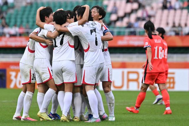 North Korea's midfielder #20 Chae Un Yong (hidden) is congratulated by teammates after scoring in the women's Group F football match between South Korea and North Korea during the 2026 Asian Games at the Shizuoka Stadium Ecopa in Fukuroi, Shizuoka prefecture on September 21, 2026. (Photo by MOHD RASFAN / AFP)