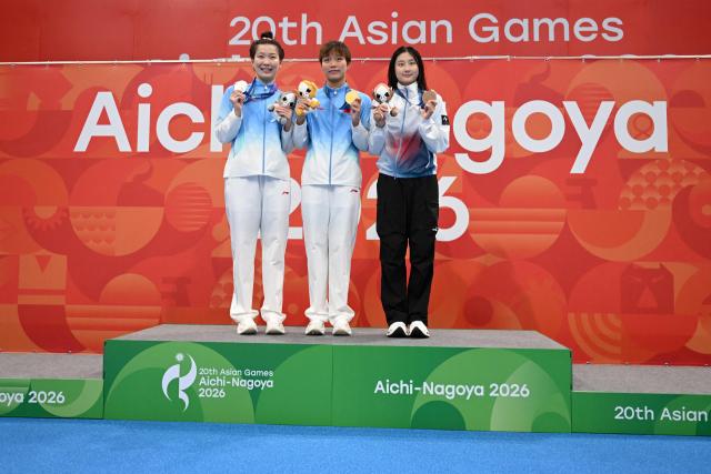 (L-R) Second-placed China's Wang Xueer, winner China's Wan Letian and third-placed South Korea's Kim Seung-won celebrate on the podium during the victory ceremony of the women's 50m backstroke swimming event during the 2026 Asian Games at the Tokyo Aquatics Centre in Tokyo on September 21, 2026. (Photo by ANDREW CABALLERO-REYNOLDS / AFP)