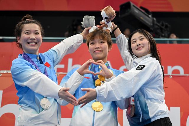 (L-R) Second-placed China's Wang Xueer, winner China's Wan Letian and third-placed South Korea's Kim Seung-won celebrate on the podium during the victory ceremony of the women's 50m backstroke swimming event during the 2026 Asian Games at the Tokyo Aquatics Centre in Tokyo on September 21, 2026. (Photo by ANDREW CABALLERO-REYNOLDS / AFP)