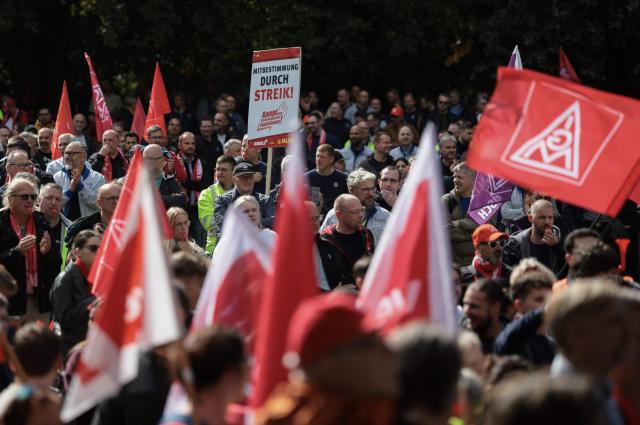 Workers wave flags of the industrial union IG Metall as they protest against job cuts in front of the commercial cars plant of German car maker Volkswagen (VW) on September 21, 2026 in Hanover, central Germany. The metalworkers' IG Metall union has called for nationwide protests at manufacturers and suppliers in the automotive industry, claiming government and management action to protect jobs and factories as the car industry hits crisis point. (Photo by Ronny HARTMANN / AFP)