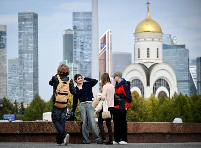 People walk through a Victory Park in front of the buildings of the Moscow International Business Centre (Moskva City) and an Orthodox church in Moscow on September 21, 2026. (Photo by Alexander NEMENOV / AFP)