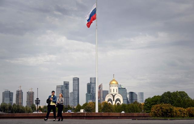 People walk through a Victory Park in front of the buildings of the Moscow International Business Centre (Moskva City) and an Orthodox church in Moscow on September 21, 2026. (Photo by Alexander NEMENOV / AFP)