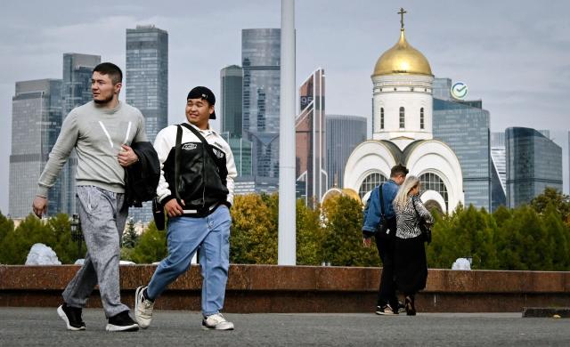 People walk through a Victory Park in front of the buildings of the Moscow International Business Centre (Moskva City) and an Orthodox church in Moscow on September 21, 2026. (Photo by Alexander NEMENOV / AFP)