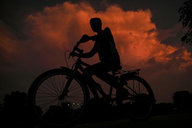 A boy rides his bicycle during dusk in Ahmedabad on September 21, 2026. (Photo by Shammi MEHRA / AFP)