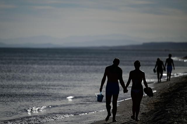 Couples walk along a beach at sunset in Portirages, southern France, on September 21, 2026. (Photo by Gabriel BOUYS / AFP)