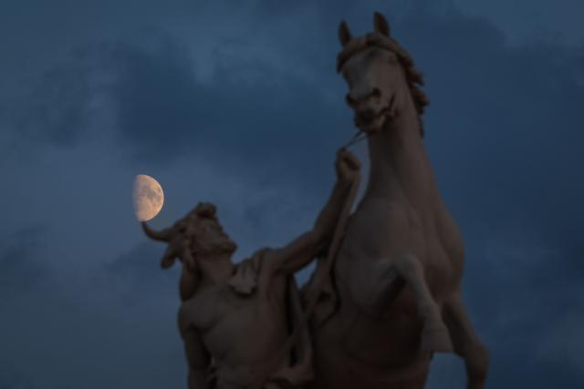 The moon can be seen behind the larger-than-life sculpture “Obotrit Taming His Horse,” which stands on the bridge in front of the Schwerin Castle, on September 20, 2026, on the eve of north-eastern Germany's Mecklenburg-Western-Pomerania's state elections. (Photo by Ronny HARTMANN / AFP)