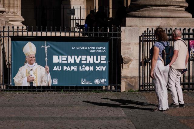 People look at a banner displayed outside Saint-Sulpice church reading "The Saint-Sulpice parish welcomes Pope Leo XIV" , four days ahead of the pontiff's apostolic visit to Paris in Paris on September 21, 2026. (Photo by Simon WOHLFAHRT / AFP)