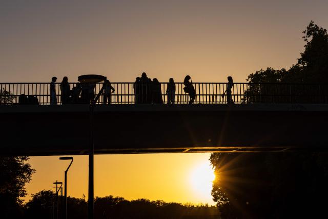 People walk across a bridge over the Deule river at sunset in Lille, northern France, on September 21, 2026. (Photo by Sameer Al-DOUMY / AFP)