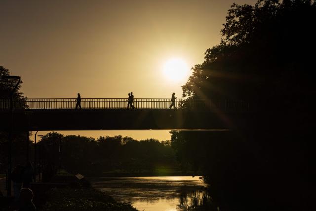 People walk across a bridge over the Deule river at sunset in Lille, northern France, on September 21, 2026. (Photo by Sameer Al-DOUMY / AFP)