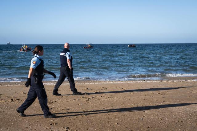 Police officers walk along the beach after migrants reached a smuggler's boat in an attempt to cross the English Channel off the beach of Merville-Franceville-Plage, northwestern France, on September 21, 2026. As crossings of the English Channel become increasingly difficult from northern French beaches, migrants are trying new routes to reach England from southern regions such as the Calvados department, where the Channel is wider than along the northern French coast. (Photo by Guillaume SALIGOT / AFP)