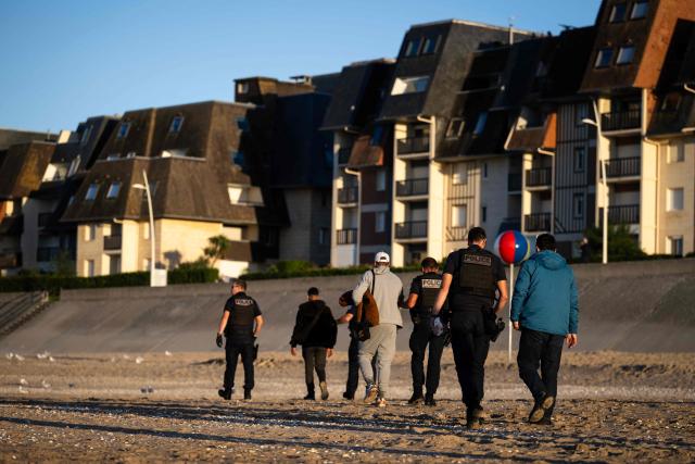 French Police officers detain migrants who attempted to reach a smugglers' boat to cross the English Channel on the beach of Cabourg, northwestern France, on September 21, 2026. As crossings of the English Channel become increasingly difficult from northern French beaches, migrants are trying new routes to reach England from southern regions such as the Calvados department, where the Channel is wider than along the northern French coast. (Photo by Guillaume SALIGOT / AFP)