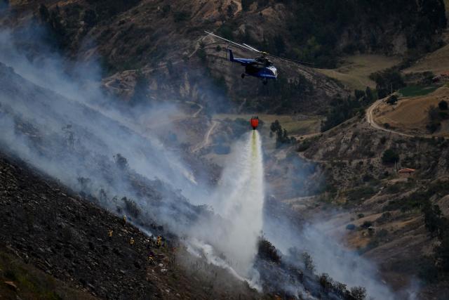 A helicopter drops water on a wildfire burning on Ritoque Hill in the municipality of Villa de Leyva, Boyaca department, Colombia, on September 21, 2026. (Photo by Raul ARBOLEDA / AFP)