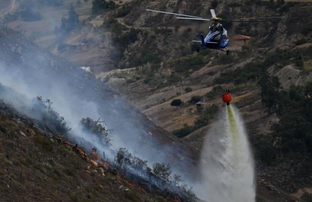 A helicopter drops water on a wildfire burning on Ritoque Hill in the municipality of Villa de Leyva, Boyaca department, Colombia, on September 21, 2026. (Photo by Raul ARBOLEDA / AFP)