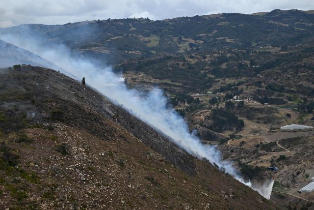 A helicopter drops water on a wildfire burning on Ritoque Hill in the municipality of Villa de Leyva, Boyaca department, Colombia, on September 21, 2026. (Photo by Raul ARBOLEDA / AFP)