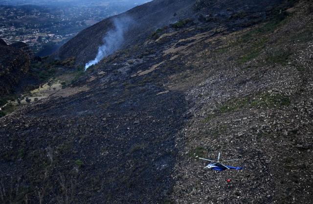 A helicopter carrying water to battle a wildfire flies above Ritoque Hill in the municipality of Villa de Leyva, Boyaca department, Colombia, on September 21, 2026. (Photo by Raul ARBOLEDA / AFP)