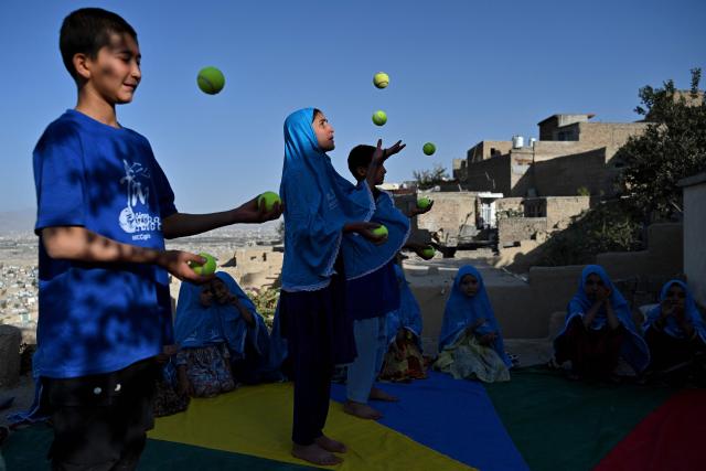 Afghan children juggle balls during a circus training session on the rooftop of a house in Kabul on September 21, 2026. (Photo by Wakil KOHSAR / AFP)