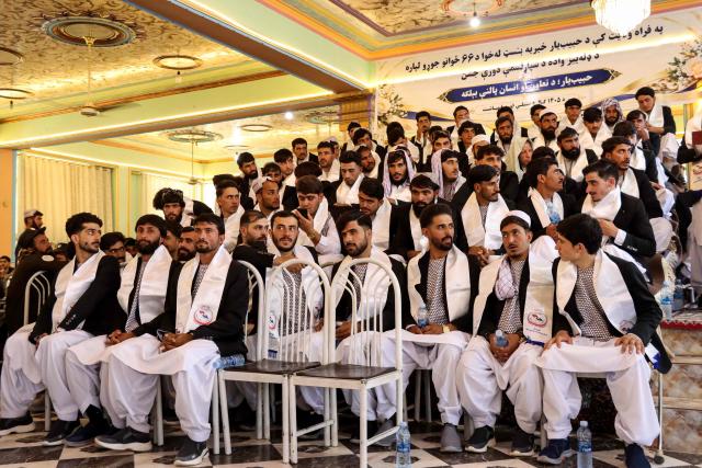 TOPSHOT - Afghan grooms gather during a mass marriage ceremony at a wedding hall in Afghanistan's Farah province on September 21, 2026. (Photo by Mohsen KARIMI / AFP)