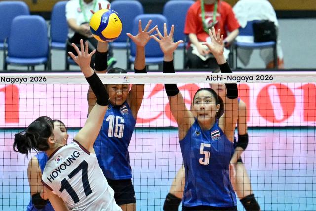 South Korea's Jung Hoyoung (L) spikes the ball as Thailand's Pimpichaya Kokram (C) and Thatdao Nuekjang block in the women's volleyball bronze medal final match between South Korea and Thailand during the 2026 Asian Games at the Park Arena Komaki in Komaki, Aichi prefecture on September 22, 2026. (Photo by MOHD RASFAN / AFP)