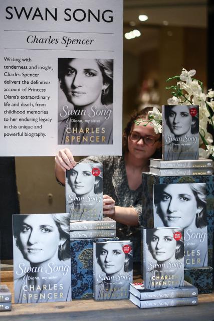 An employee puts out copies of "Swan Song: Diana, My Sister", Charles Spencer's book about his late sister Princess Diana, into a window display at a bookstore in central London on September 22, 2026. The book, reportedly packed with explosive revelations, was published on September 22 after searing extracts prompted a rare and sharp rebuttal from Britain's King Charles III. Almost three decades after Diana was killed in a car crash in Paris in 1997, people remain fascinated by her life and tragic death. (Photo by Henry Nicholls / AFP)