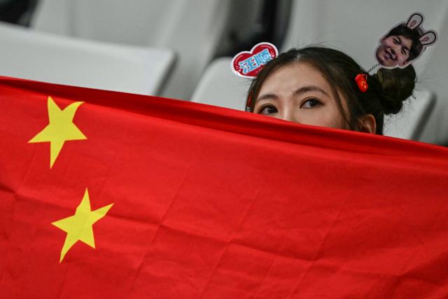 A supporter holds a Chinese flag at the evening session of the swimming event during the 2026 Asian Games at the Tokyo Aquatics Centre in Tokyo on September 22, 2026. (Photo by ANDREW CABALLERO-REYNOLDS / AFP)