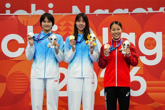 Silver medallist China's Sun Mingxia (L), gold medallist China's Peng Xuwei (C) and bronze medallist Japan's Rio Shirai (R) celebrate on the podium during the victory ceremony of the women's 200m backstroke swimming event during the 2026 Asian Games at the Tokyo Aquatics Centre in Tokyo on September 22, 2026. (Photo by Yuichi YAMAZAKI / AFP)