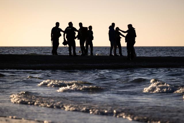 French Police officers detain migrants who attempted to reach a smugglers' boat to cross the English Channel on the beach of Cabourg, northwestern France, on September 21, 2026. As crossings of the English Channel become increasingly difficult from northern French beaches, migrants are trying new routes to reach England from southern regions such as the Calvados department, where the Channel is wider than along the northern French coast. (Photo by Guillaume SALIGOT / AFP)