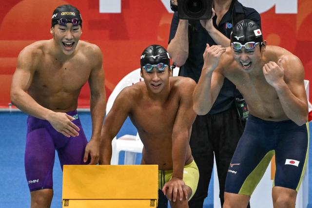 Japan's Japan's Hidekazu Takehara, Shin Ohashi and Shoon Mitsunaga cheer as their teammante swims to the finish line while competing in the final of the men's 4 x 100m medley relay swimming event during the 2026 Asian Games at the Tokyo Aquatics Centre in Tokyo on September 22, 2026. (Photo by ANDREW CABALLERO-REYNOLDS / AFP)