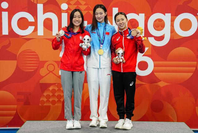Silver medallist Singapore's Gan Ching Hwee (L), gold medallist China's Li Bingjie (C) abd bronze medallist Japan's Ichika Kajimoto (R) celebrate on the podium during the victory ceremony of the women's 400m freestyle swimming event during the 2026 Asian Games at the Tokyo Aquatics Centre in Tokyo on September 22, 2026. (Photo by Yuichi YAMAZAKI / AFP)