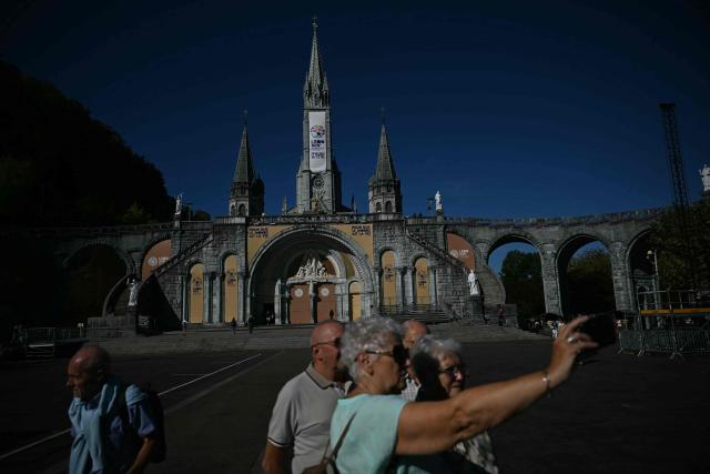 People gather in front of the Basilique Notre-Dame du Rosaire five days ahead of a visit by Pope Leo XIV to the site as part of his apostolic trip to France, in Lourdes on September 22, 2026. (Photo by lionel BONAVENTURE / AFP)