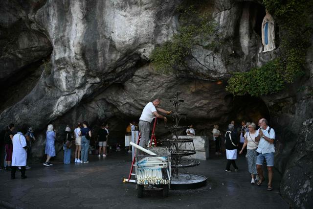 An employee of the Notre Dame Sanctuary sets up candles at the Massabielle cave five days ahead of a visit by Pope Leo XIV to the site as part of his apostolic trip to France, in Lourdes on September 22, 2026. (Photo by lionel BONAVENTURE / AFP)