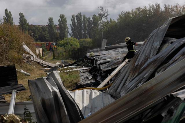 Ukrainian firefighters are working at a destroyed warehouse following the recent Russian drone strike in Kyiv region on September 22, 2026, amid the Russian invasion of Ukraine. (Photo by Tetiana DZHAFAROVA / AFP)