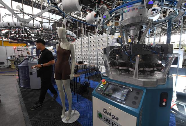 A man walks past textile machines during the Nextech textile trade show in Medellin, Colombia on September 22, 2026. (Photo by Jaime SALDARRIAGA / AFP)