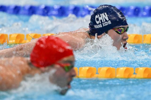 China's Wang Xizhe (R) and Bahrain's Mikhail Arkhangelskiy (L) compete in a heat of the men's 100m butterfly swimming event during the 2026 Asian Games at the Tokyo Aquatics Centre in Tokyo on September 23, 2026. (Photo by ANDREW CABALLERO-REYNOLDS / AFP)