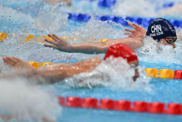 China's Wang Xizhe (top) and Bahrain's Mikhail Arkhangelskiy (below) compete in a heat of the men's 100m butterfly swimming event during the 2026 Asian Games at the Tokyo Aquatics Centre in Tokyo on September 23, 2026. (Photo by ANDREW CABALLERO-REYNOLDS / AFP)