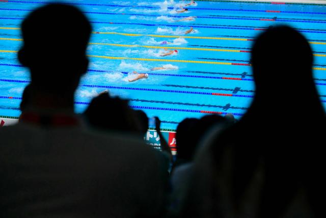 Supporters watch swimmers compete in a heat of the men's 100m butterfly swimming event during the 2026 Asian Games at the Tokyo Aquatics Centre in Tokyo on September 23, 2026. (Photo by Yuichi YAMAZAKI / AFP)