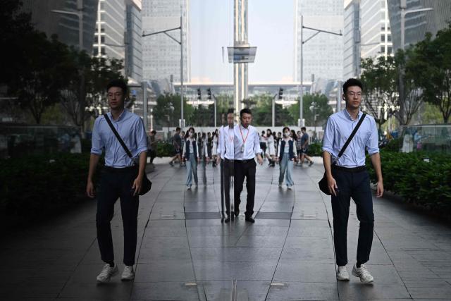 A man walks past an office building in the central business district in Beijing on September 23, 2026. (Photo by GREG BAKER / AFP)