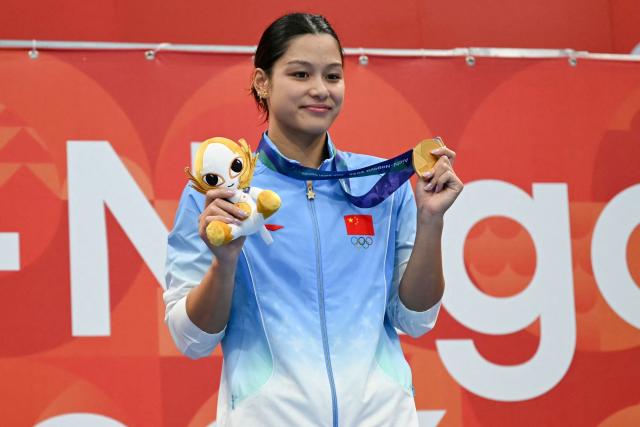 China's swimmer Yiting Yu celebrates with her gold medal on the podium during the victory ceremony of the women's 100m butterfly swimming event during the 2026 Asian Games at the Tokyo Aquatics Centre in Tokyo on September 23, 2026. (Photo by ANDREW CABALLERO-REYNOLDS / AFP)