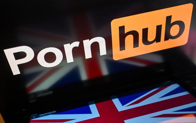 (FILES) An illustration photograph taken on January 29, 2026 shows the logo of the website Pornhub and a British flag, arranged for a photograph on a laptop and smartphone, at a residential property in Guildford, south of London. Britain's media regulator Ofcom said on September 23, 2026 it had opened an investigation into Aylo, the parent company of Pornhub, over concerns that children were potentially accessing pornography online. (Photo by Justin TALLIS / AFP)