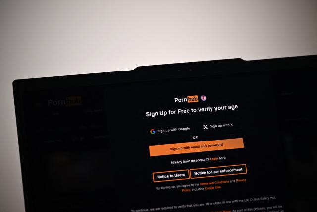 (FILES) An illustration photograph taken on January 29, 2026 shows the age-restriction warning screen of the website Pornhub, arranged for a photograph on a laptop screen at a residential property in Guildford, south of London. Britain's media regulator Ofcom said on September 23, 2026 it had opened an investigation into Aylo, the parent company of Pornhub, over concerns that children were potentially accessing pornography online. (Photo by Justin TALLIS / AFP)