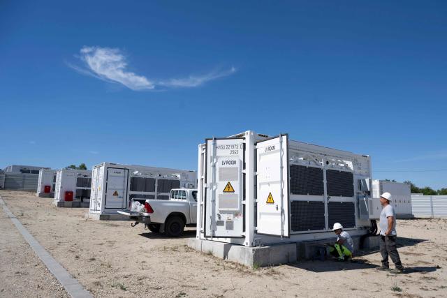 This photograph taken on September 18, 2026, shows workers checking battery containers in the Suntera Re's 450 MWh battery energy storage facility near the village of Pyasachevo. As Eastern Europe's power sector has taken a hit from a record drought, Bulgaria has benefitted from a surge in solar-powered battery projects across the country. Around a hundred large battery energy storage system (BESS) sites are now operating, most of them built in the past two years. (Photo by Nikolay DOYCHINOV / AFP)